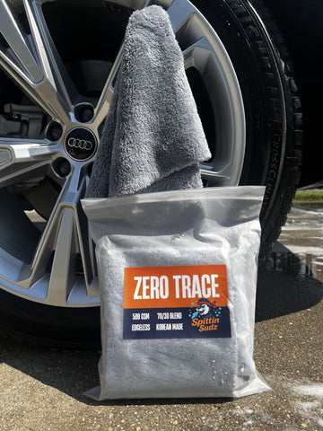 Spittin Sudz Zero Trace premium Korean microfiber finishing towel displayed in front of a clean car wheel